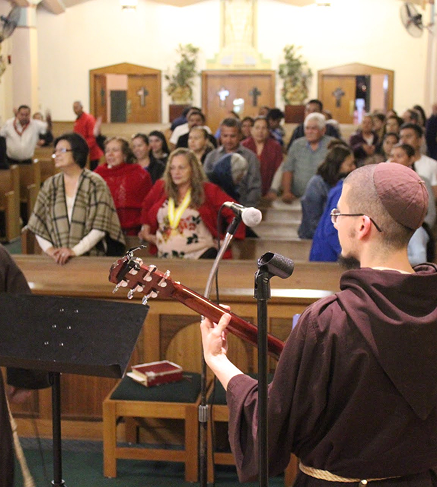 Friar playing guitar during worship
