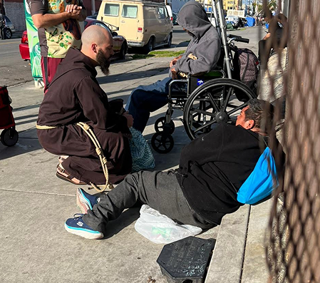 Friar kneeling and talking to someone on the ground