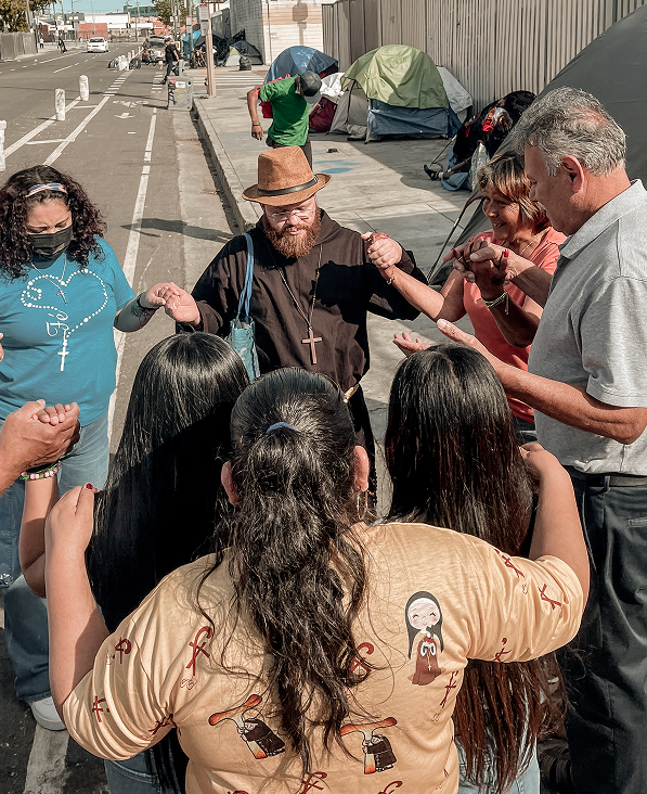 Friar and young people holding hands in a circle