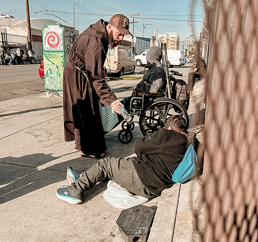 Friar giving water to a person on the ground