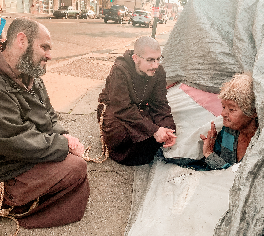 Friars talking with a homeless person