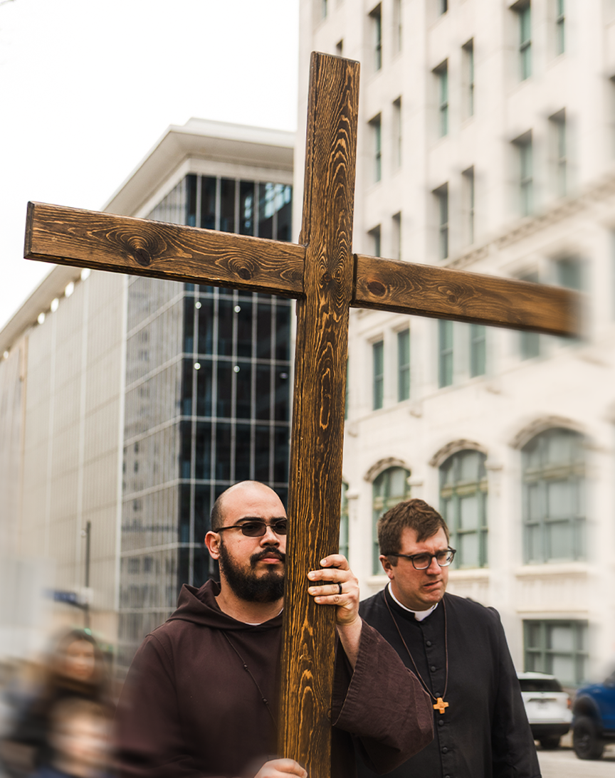 Friars carrying a wooden cross in the city